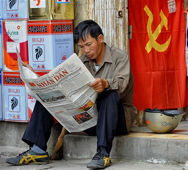 Một công nhân giờ nghỉ đọc báo Nhân Dân. AFP